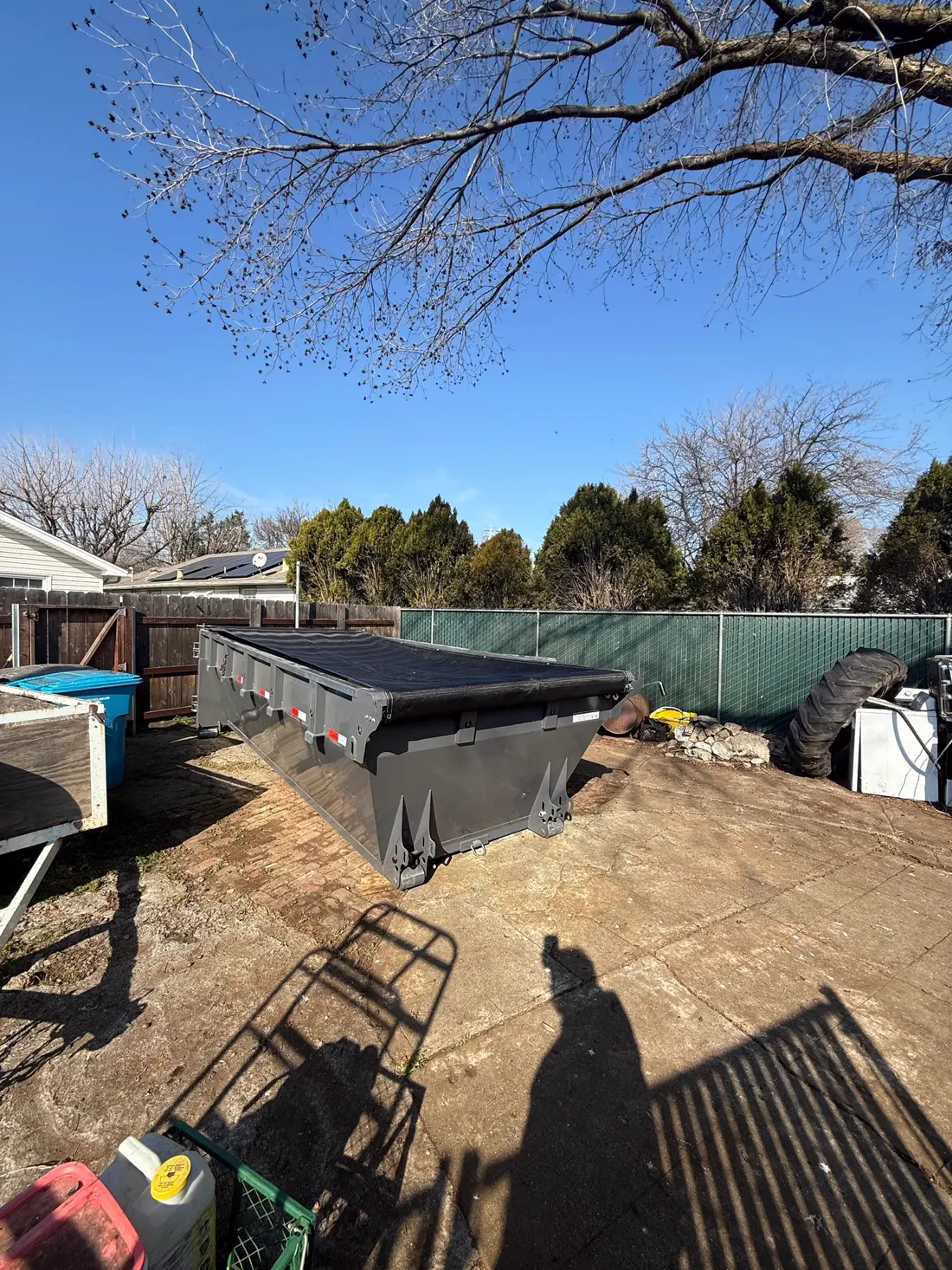 Dumpster secured with a mesh cover in a backyard
