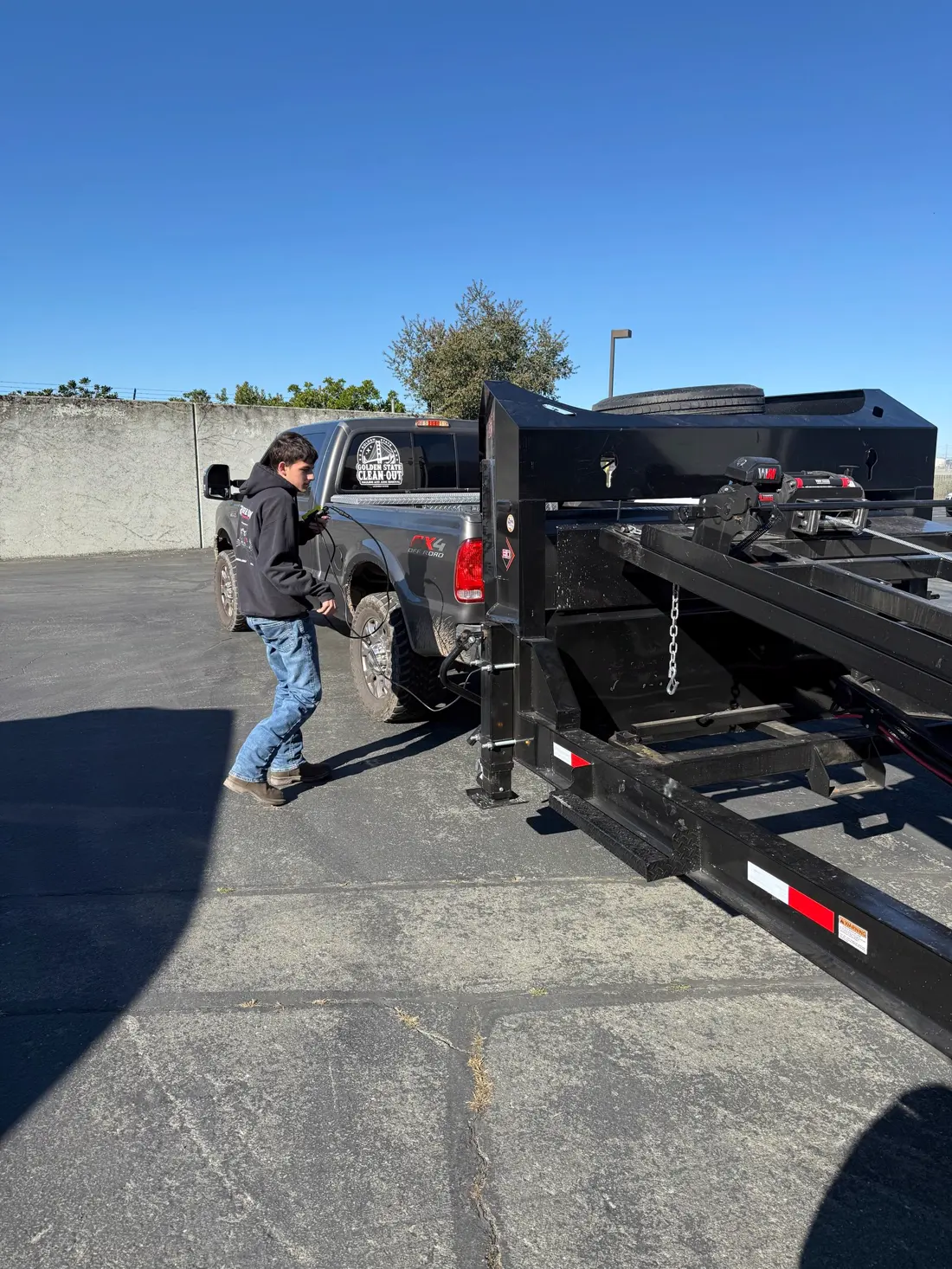 Crew member hitching the roll-off trailer to the Golden State Cleanout truck