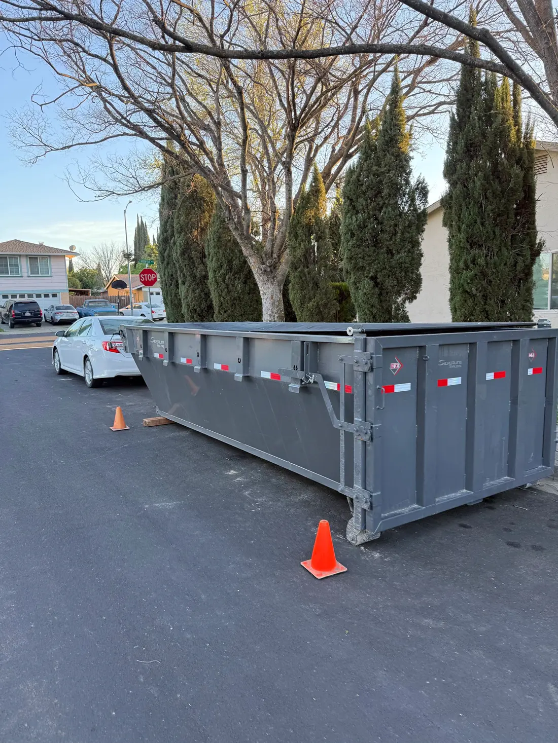 Curbside dumpster placement marked with safety cones