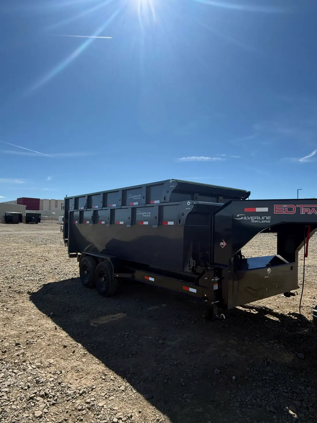 Stacked roll-off dumpsters on the gooseneck trailer in the sun