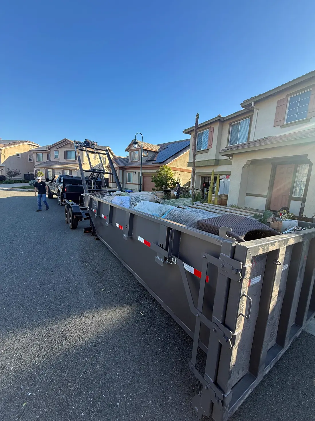 Roll-off dumpster loaded with a full property cleanout in a residential neighborhood