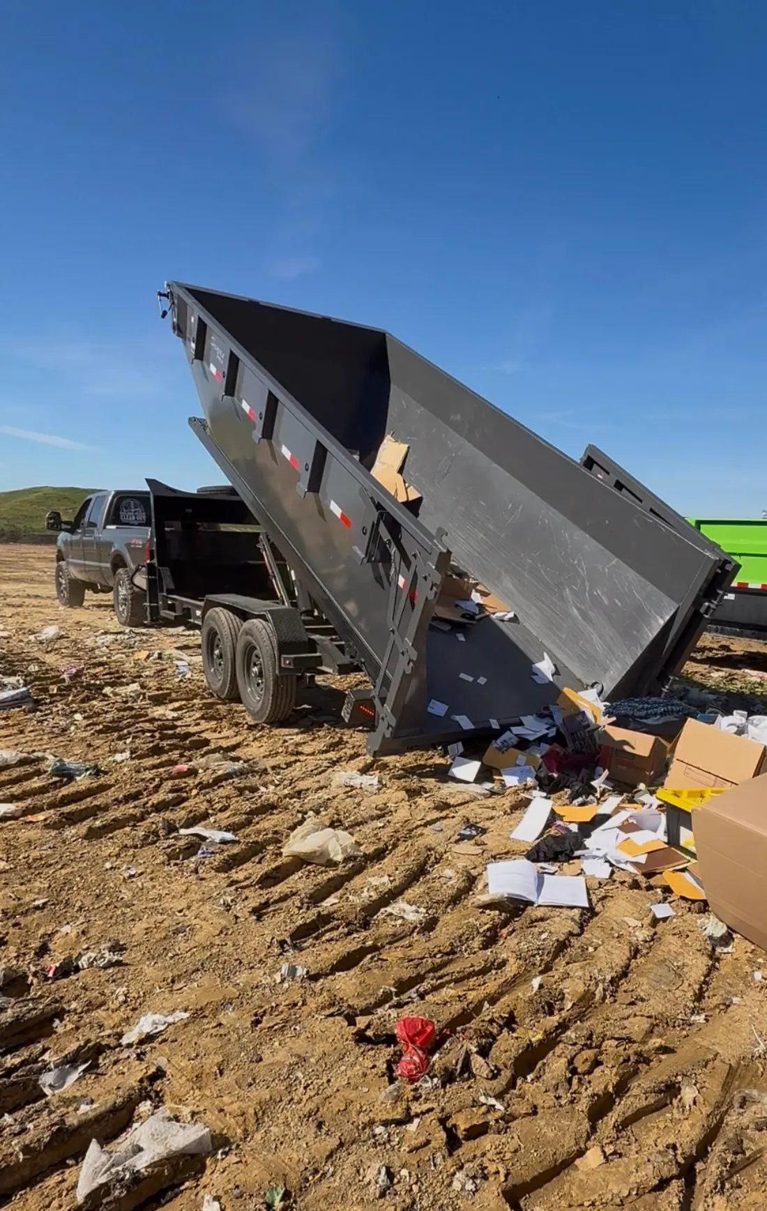 Dumpster tilted up dumping a load at the landfill